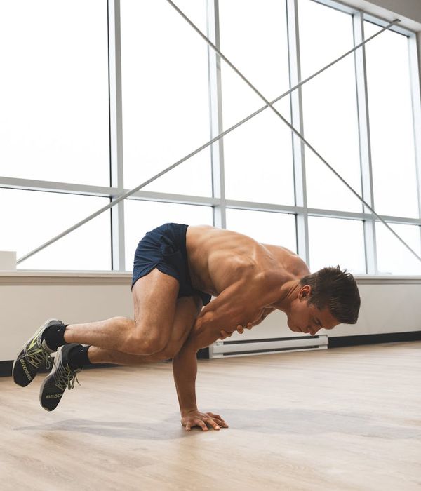Man performing a core strength exercise in a modern, dark gym.